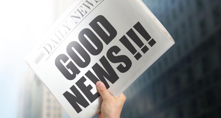 Image of a hand holding a newspaper that says 'Good News!!!'