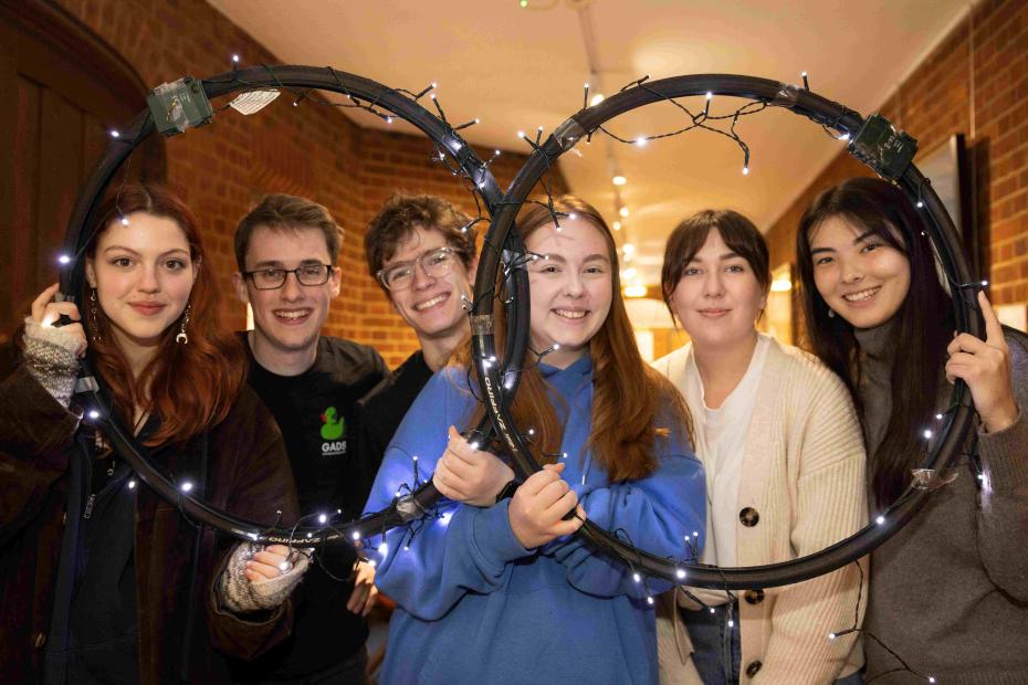 6 students posing behind two overlapping circles with fairy lights