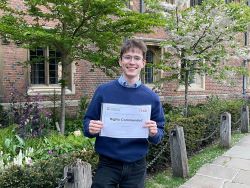 Harry Goolnik stands outside holding up his award, a certificate.