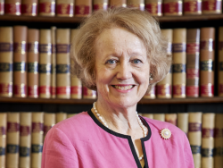 Lady Arden stands in front of a bookcase full of legal texts.