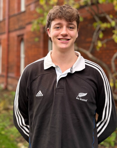Sam stood outside of Girton wearing an All Blacks rugby shirt