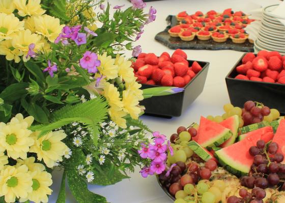 flowers and fruit platters on white table clothed tables