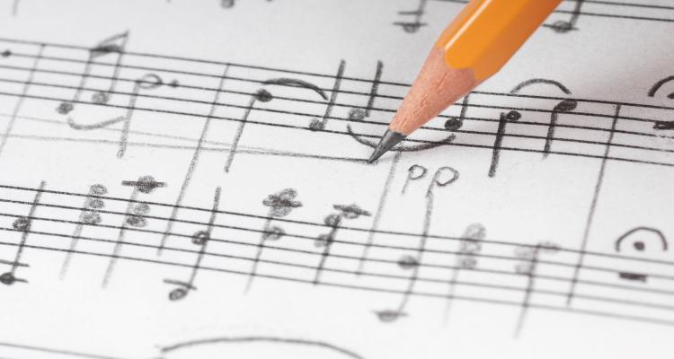 pencilled marked music composition on white paper with scores, a yellow pencil marks the page