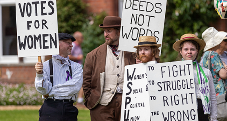 Group holding signs in support of votes for women