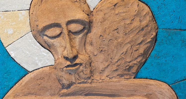 a relief clay sculpture of a person being embraced by Jesus Christ by Lubo Michalko, displayed in the Quo Vadis Catholic. 