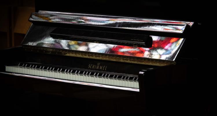 Piano in Chapel with reflection of stained glass window