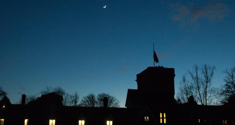 Girton College Tower, flag at half-mast, in darkness