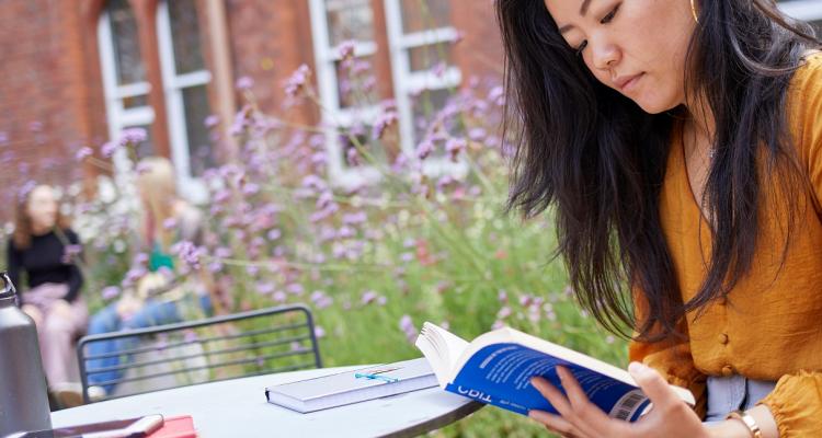 Girton College student studying outside on campus