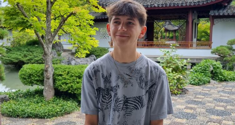 Girton Student, Felix Elliott, sitting on a wall in a courtyard