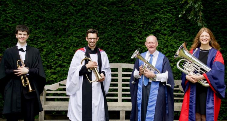 Four College musicians including the Mistress with brass instruments standing in the grounds