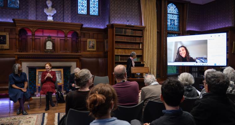 Winner of the William Dusinberre Prize 2025, Carson Eckhard, smiles from a screen as she joined us remotely. The audience smiles back.