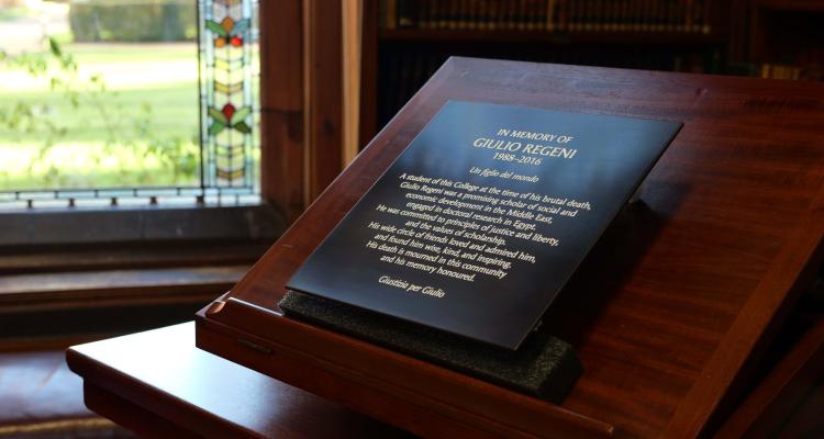 The plaque resting on a easel, in front of the stain glass window in the Stanley Library, Girton College