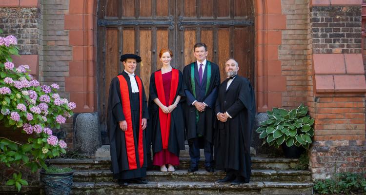 Dr Seb Falk (Praelector), Dr Elisabeth Kendall (Mistress of Girton College), Dominic Slade, and Dr James Wade (Vice-Mistress of Girton College) standing on the steps in Eliza Baker Courtyard