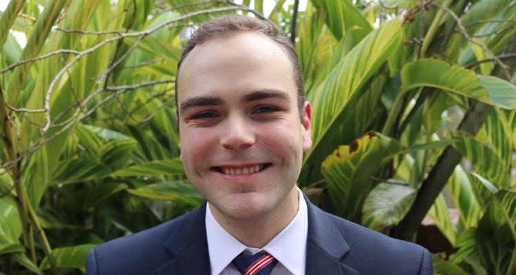 Portrait of Girton College Postgraduate student Sebastian Delgado Suarez (MPhil 2023), positioned in front of a background of large leaf foliage