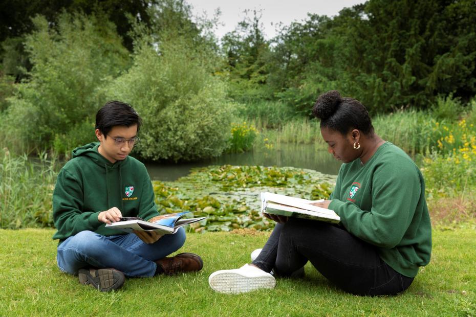 Students sitting by pond reading